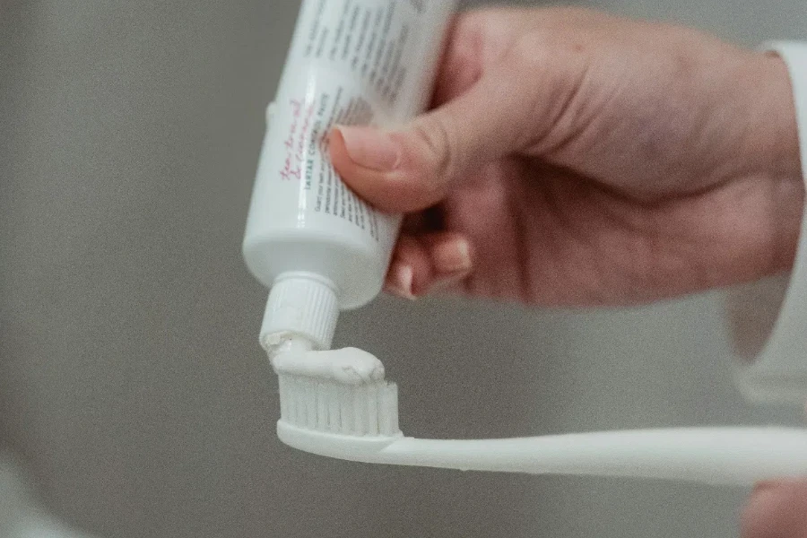 Person Putting Toothpaste On Toothbrush