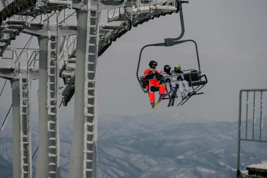 Two people riding a ski lift on top of a mountain