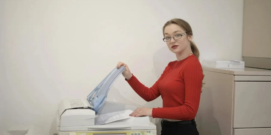 Serious female office worker using printer in workplace