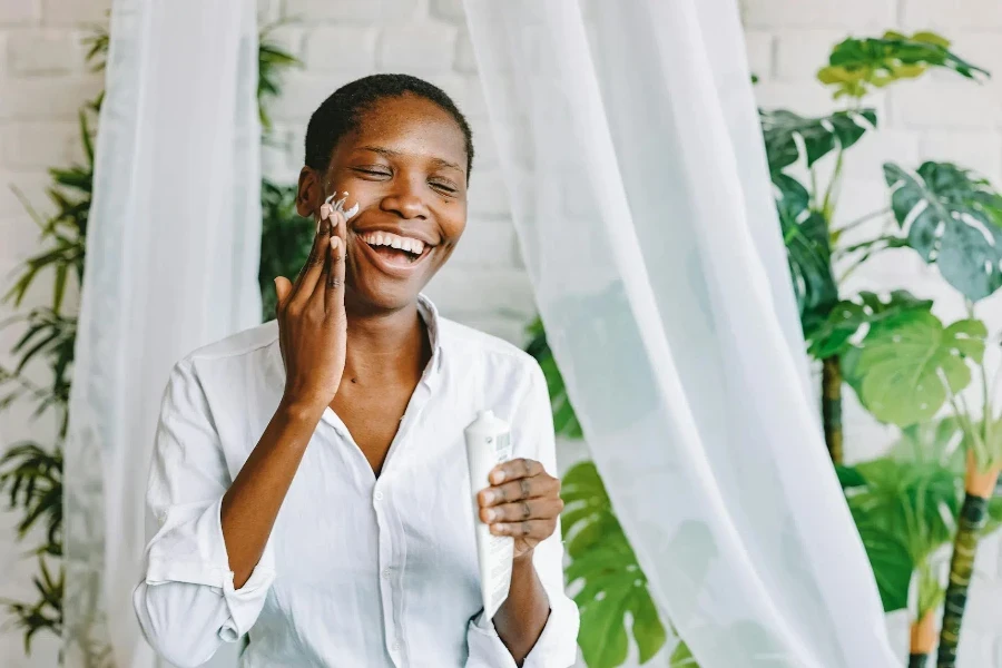 Woman Applying Face Cream and Smiling