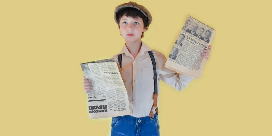 Pensive boy standing with old newspapers