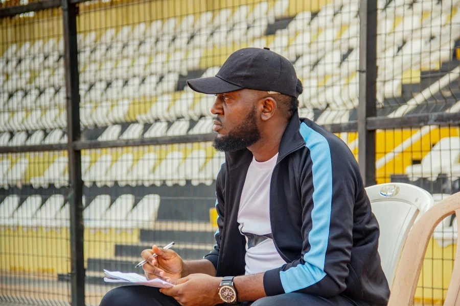 Man in Cap Sitting and Taking Notes at Stadium