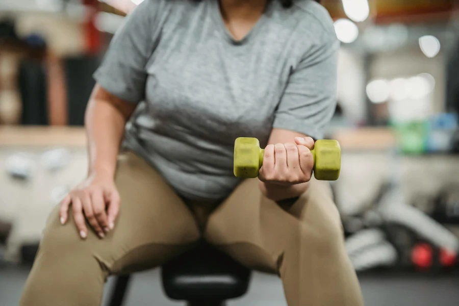 Crop black woman doing exercises with dumbbells