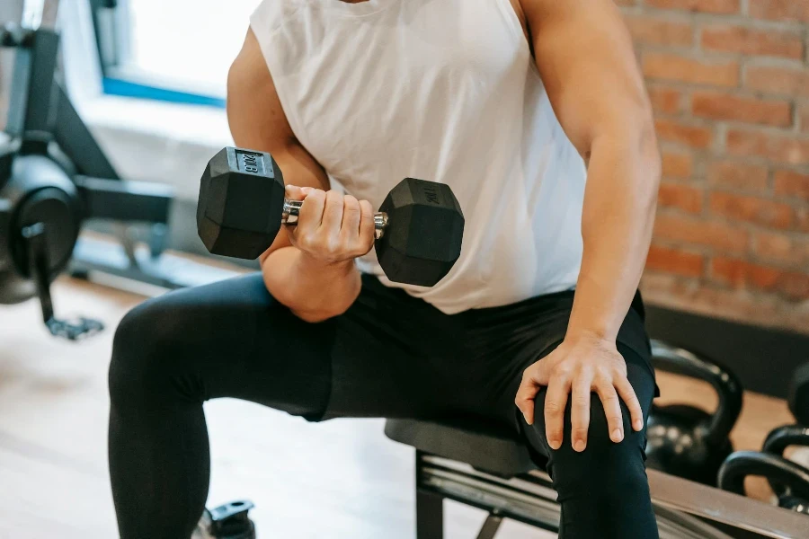 strong male pumping bicep while lifting heavy metal dumbbell