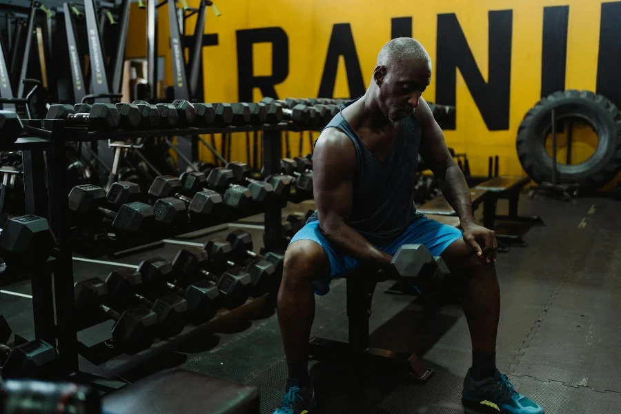 Man in Blue Tank Top and Shorts Exercising With a Dumbbell