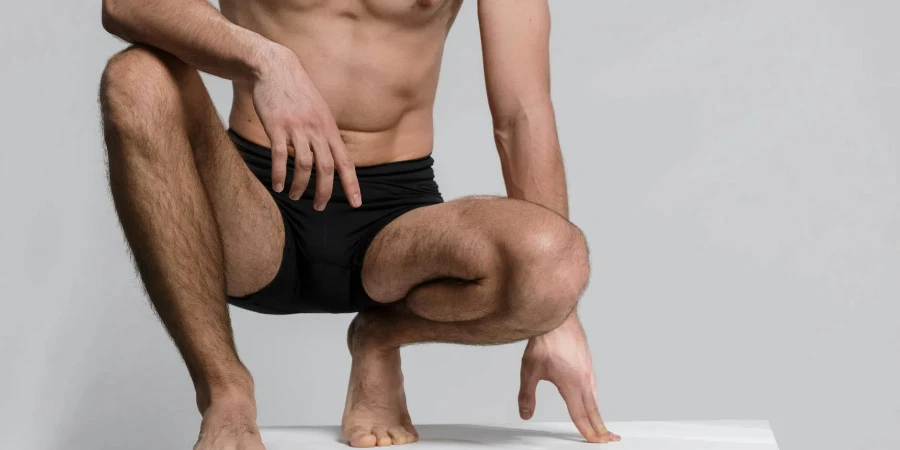 A Close-Up Shot of a Shirtless Man Squatting on a Platform