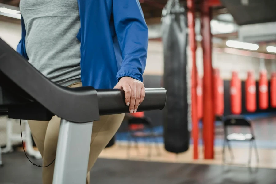 Crop woman standing on treadmill in gym