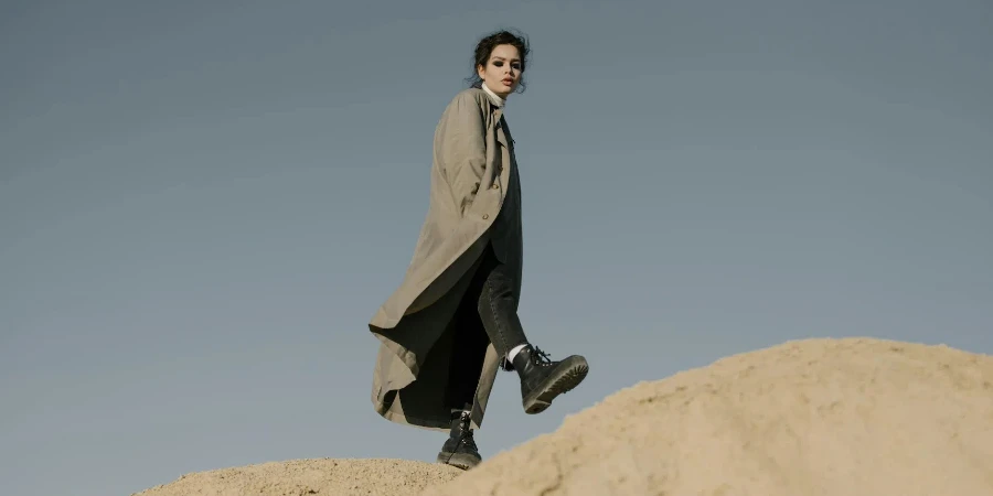 Man in Black Coat Sitting on Brown Rock