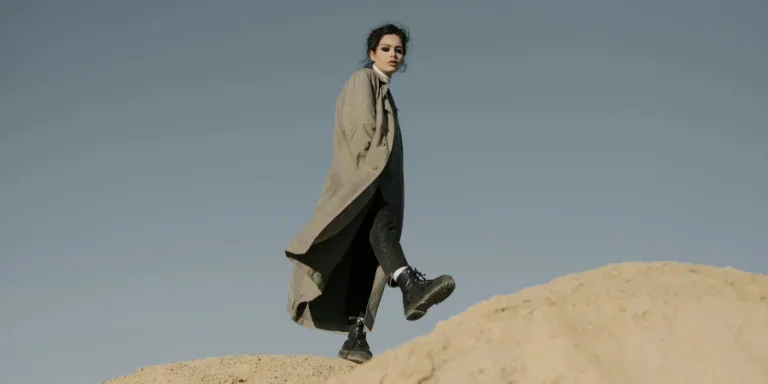 Man in Black Coat Sitting on Brown Rock