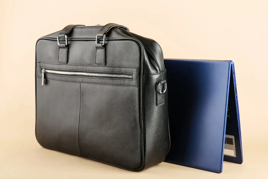 la borsa in pelle da uomo e il laptop sono su uno sfondo marrone chiaro