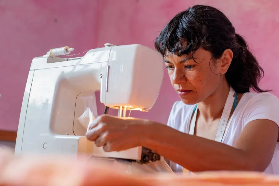 old woman is using handheld sewing machine