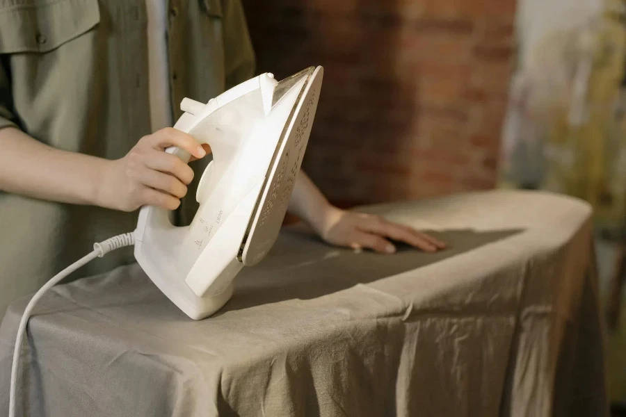 Person holding an iron on an ironing board