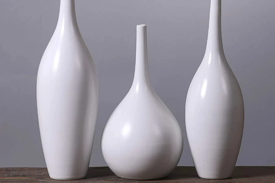 Three shiny ceramic narrow neck vases on a grey background