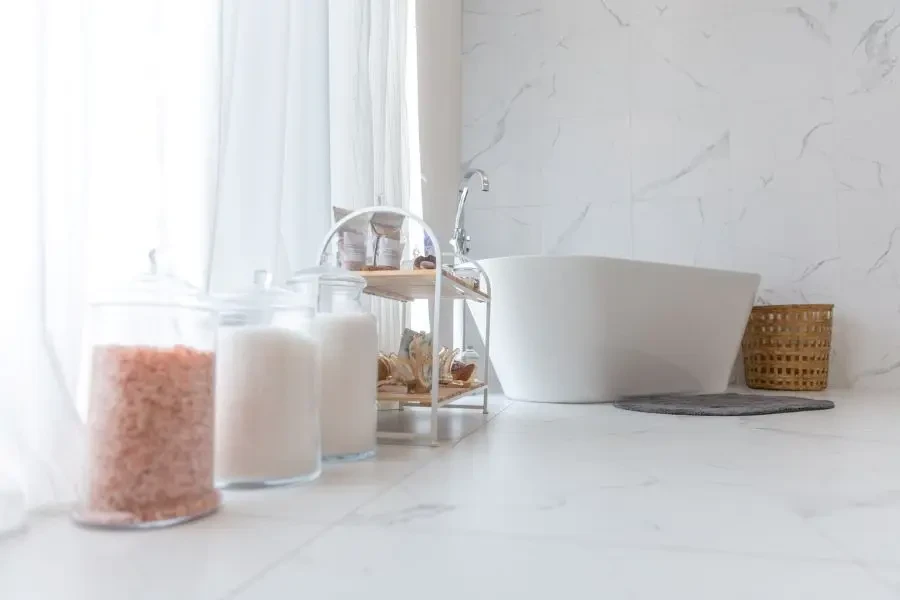 view of the inside of a minimalistic white bathroom with a tub and epsom salts