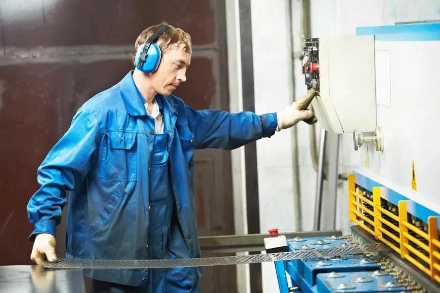 worker at workshop operating guillotine shears machine