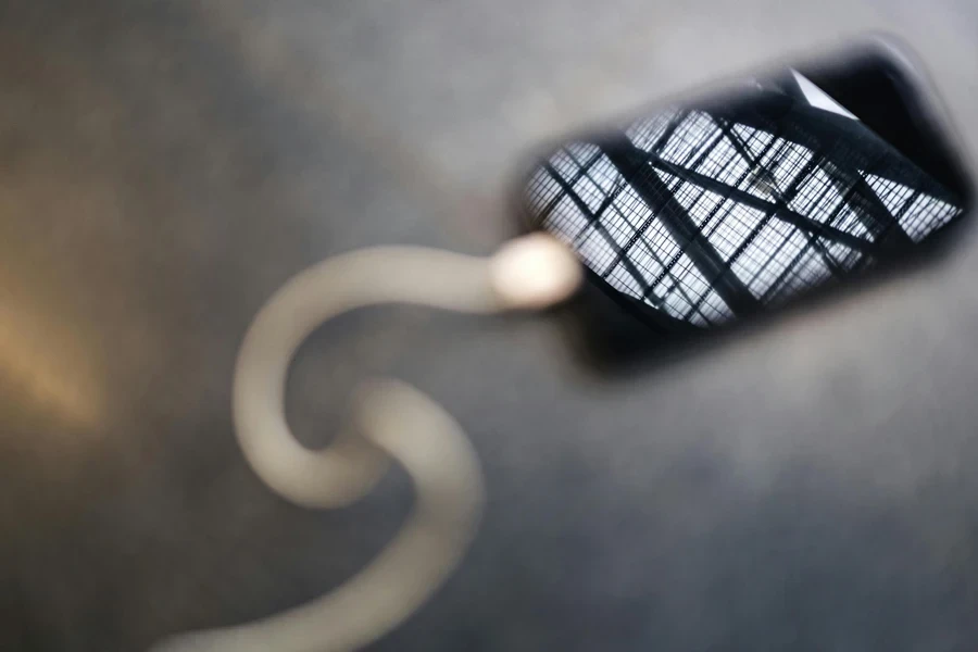 A Charging Cellphone on Gray Surface with a Steel Fence Reflection on Srcreen