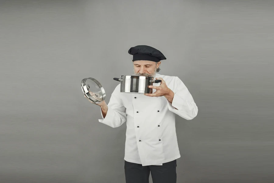 A Man Smelling the Food in the Stainless Steel Soup Pot