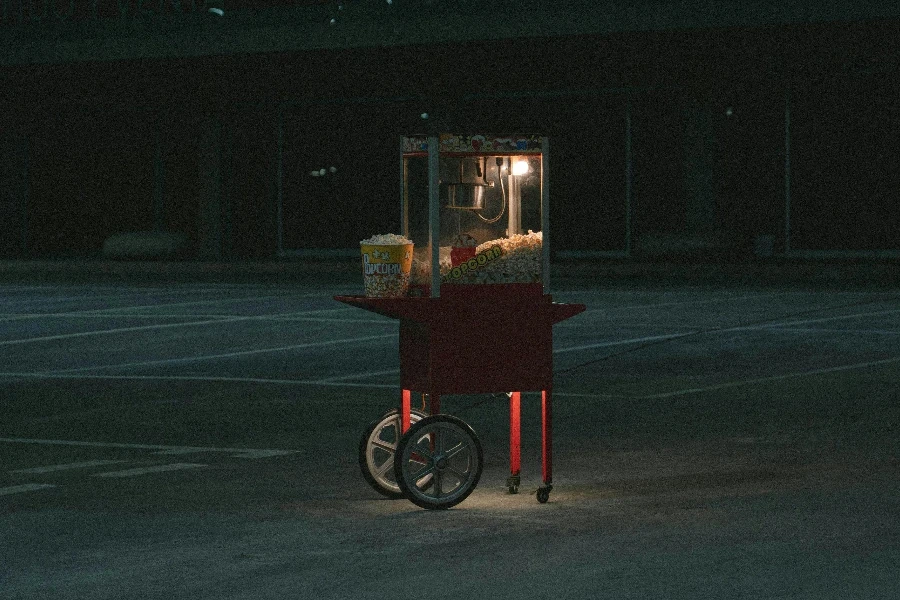 A Red Popcorn Machine on Road at Night