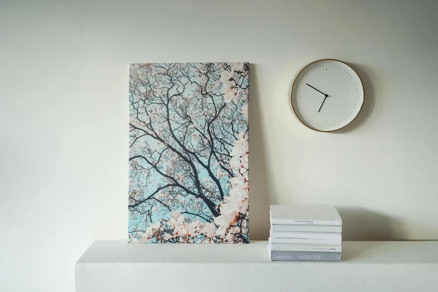 A Round Wall Clock Near the Painting and Books on the Table