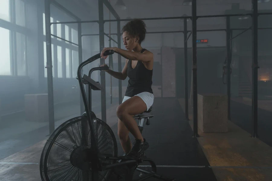 A Woman in Black Tank Top Sitting on an Air Bike