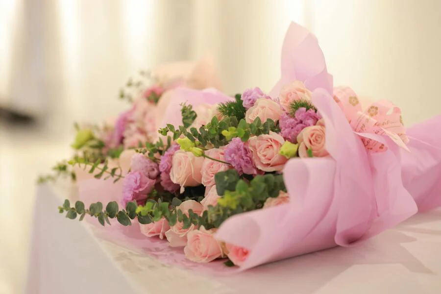 A bouquet of roses wrapped in pink paper