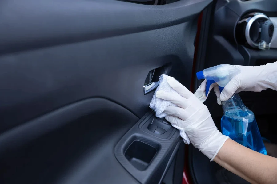 A driver disinfecting inside the car with spray and rag