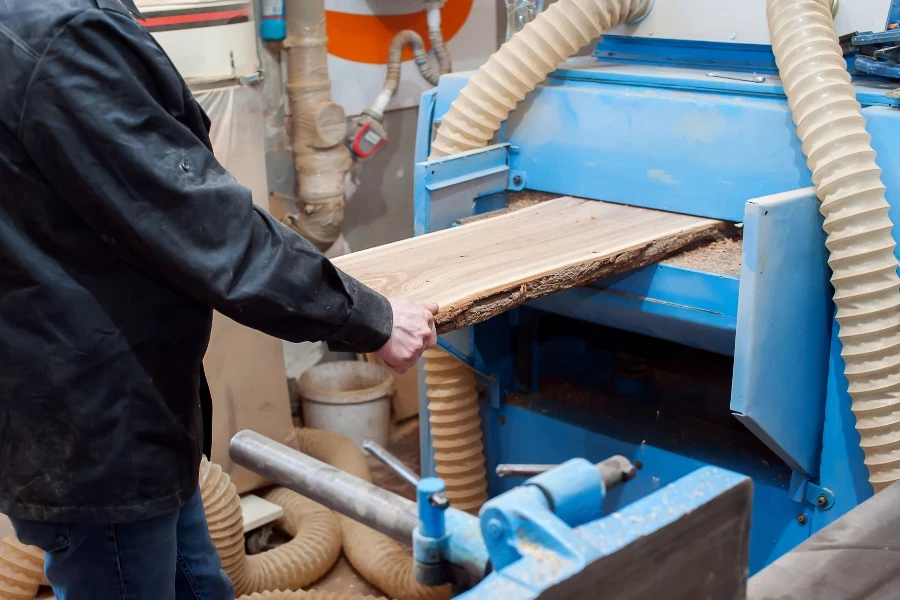 A male carpenter works in a carpentry workshop on a thickness gauge