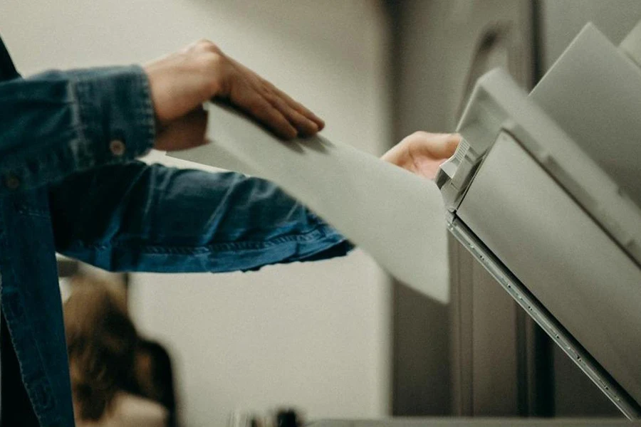 A man inserting printing papers into a  multi-purpose laser printer