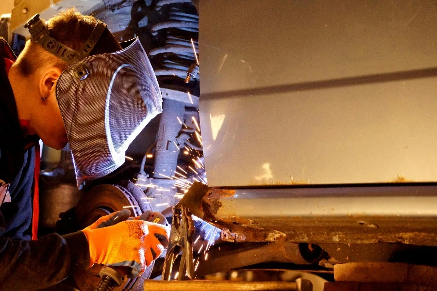 A man welding on a car in a garage by Michael Kabus