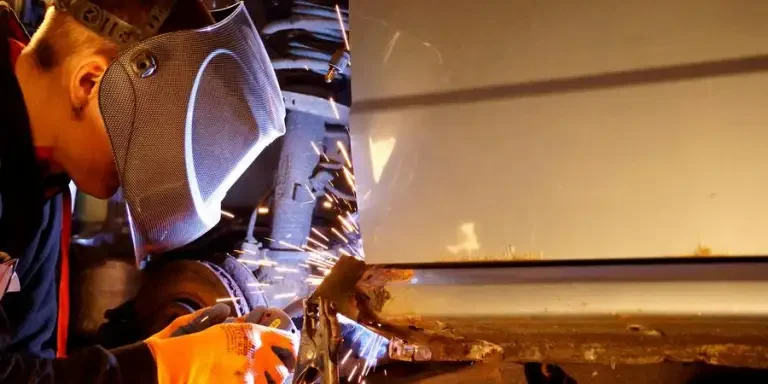 A man welding on a car in a garage by Michael Kabus