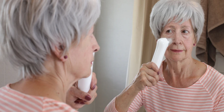 A senior woman in her sixties is doing some deep pore cleaning