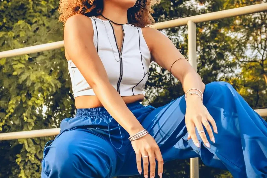 A woman in blue pants and white top is sitting on a bench by Kevyn Costa