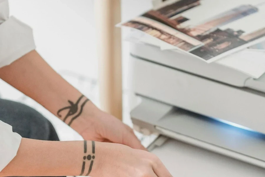 A woman placing papers in an inkjet printer for photo-printing