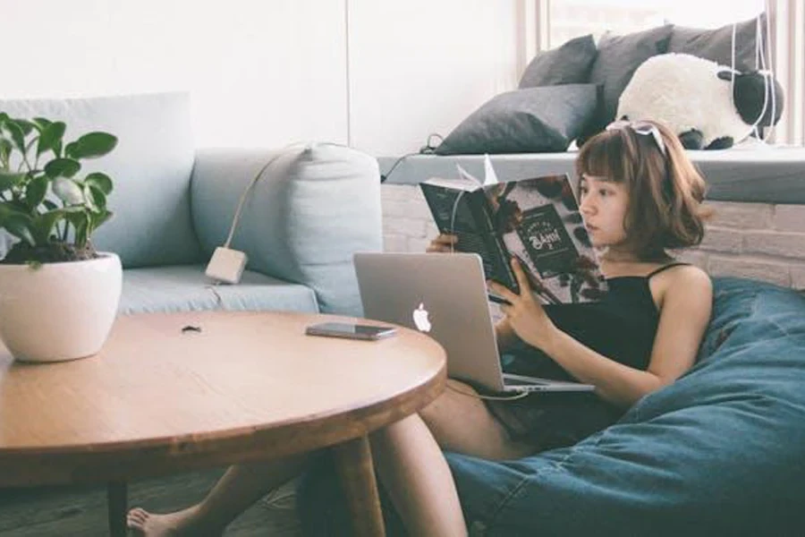 A woman sitting on a bean bag reading a book