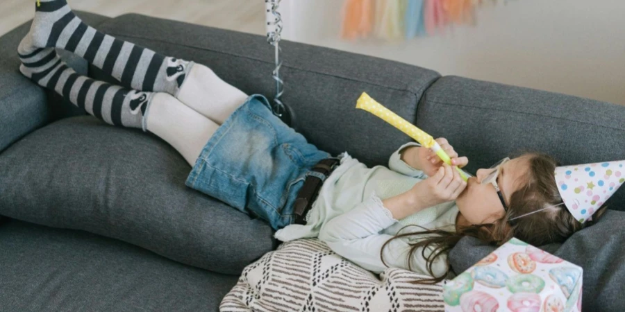 A young girl lying on the couch with balloons