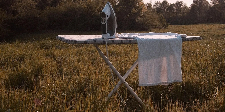 An ironing board sits in a field with a white towel