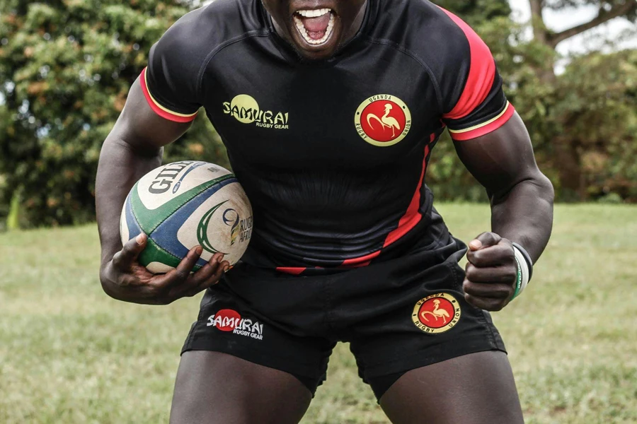 Athlete holding a rugby ball in shorts and jersey
