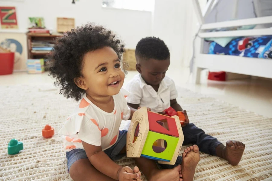 Baby Boy And Girl Playing With Toys In Playroom