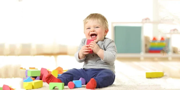 Baby lacht und spielt mit Spielzeug auf einem Teppich