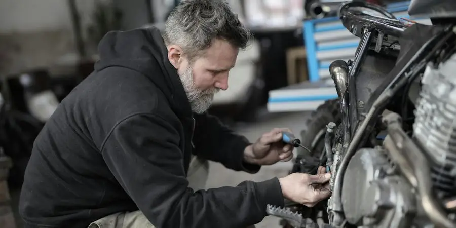 Bearded man fixing motorcycle in workshop by Andrea Piacquadio