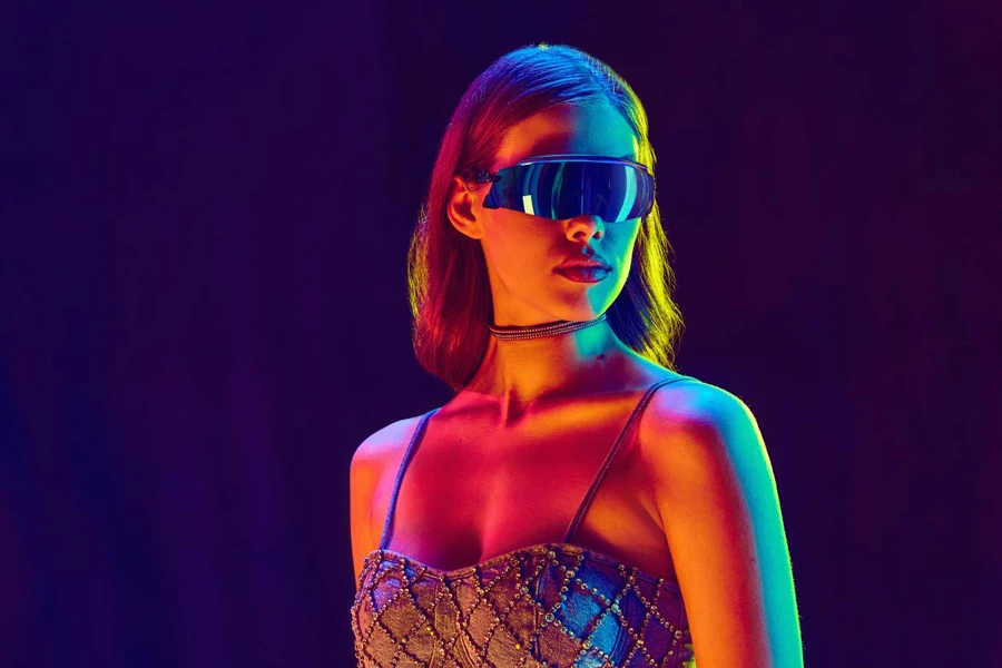 Beautiful fashion AI model, serious woman wearing fashionable clothes, crop top and black sunglasses posing over violet background in neon light.