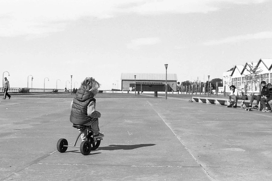 Black and White Photo of a Kid Riding a Tyicycle