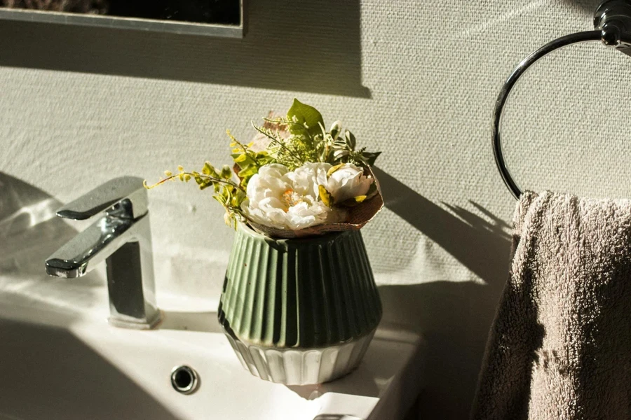 Bouquet of fresh flowers in vase on sink in bathroom