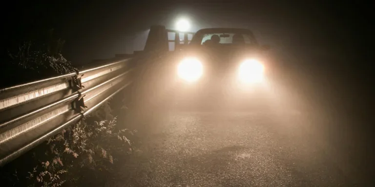 Bright Lights From a Car Driving on a Dark Road