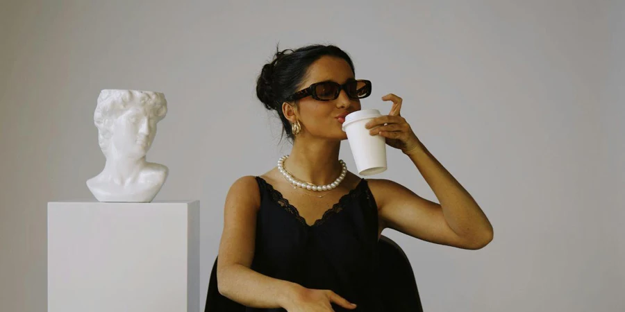 Brunette Woman in Black Dress Sitting and Drinking