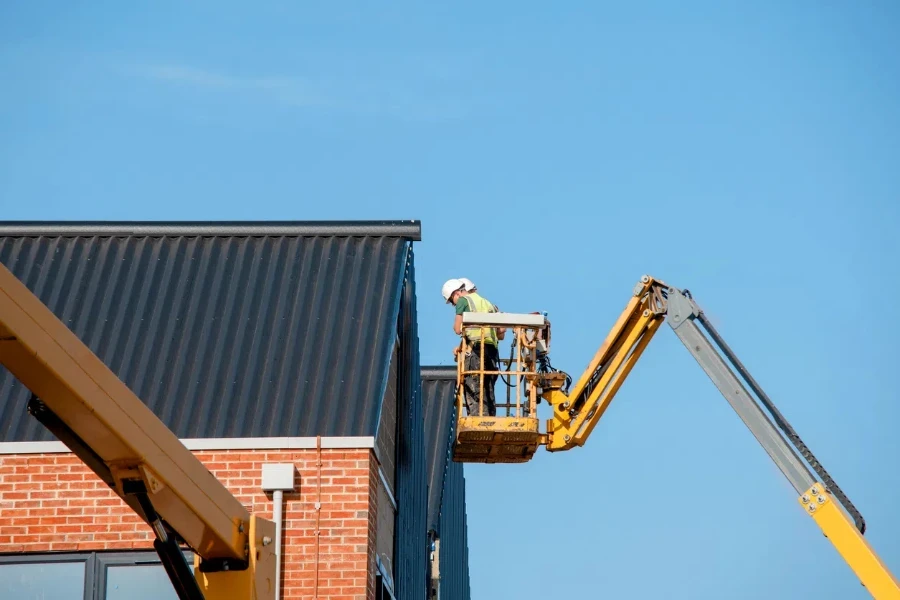 Builders working off Telescopic Boom Lift while fitting insulated sandwich panels to the facade of a new multistorey residential building