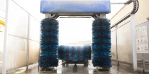 Автомобиль, покрытый активной пеной во время мойки автомобиля, попадает в щетки стиральной машины на размытом фоне 1