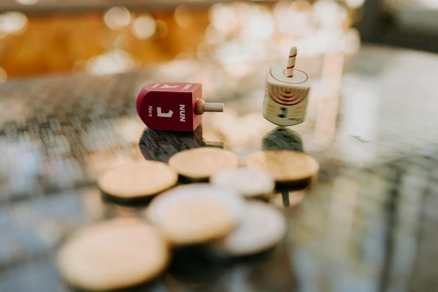 Close-Up Photo Of Gold Coins Near Dreidel Spinners