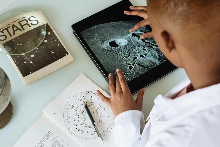 Crop African American student studying craters of moon on tablet at observatory