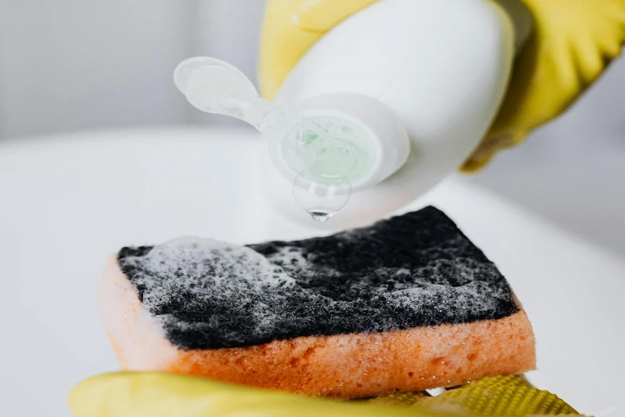 Crop person pouring detergent on sponge